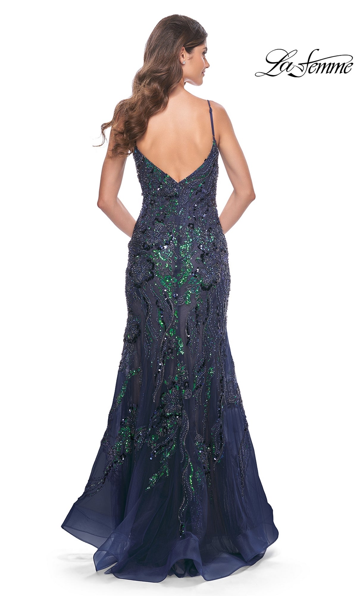 Woman in the Le Femme Sequin-Lace Long Mermaid Prom Dress 32049, featuring navy and green sequin-lace, thin straps, and a low back, stands facing away from the camera.